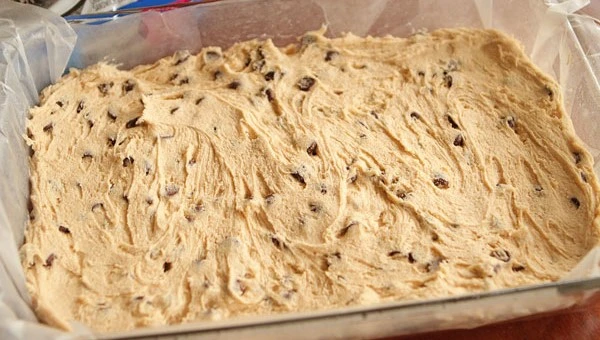 La pâte à cookie est ensuite déposée dans le moule préparé et lissée pour